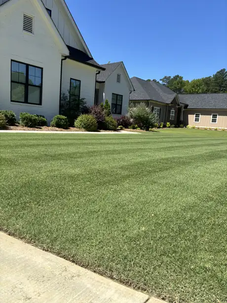 A clean, weed-free front lawn at a white farmhouse-style home