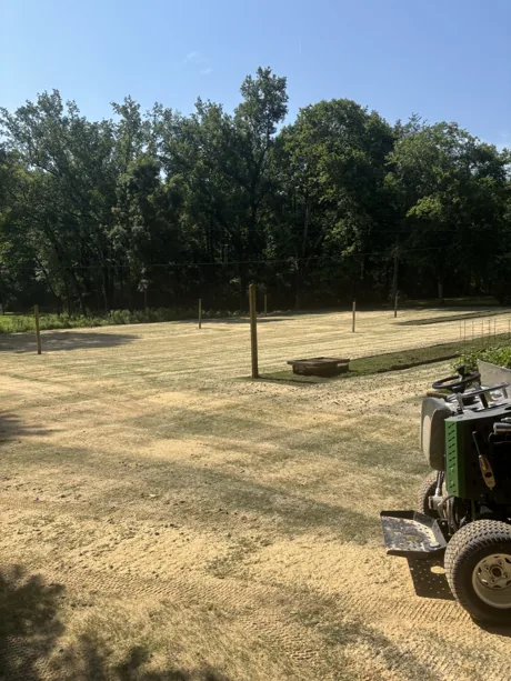 Rows of topdressing sand laid across a lawn part-way through a leveling pass