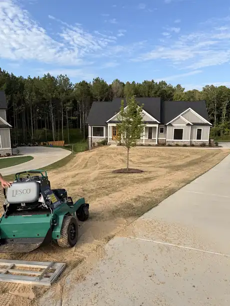 A spreader unloading at a new-build home with a freshly topdressed lawn
